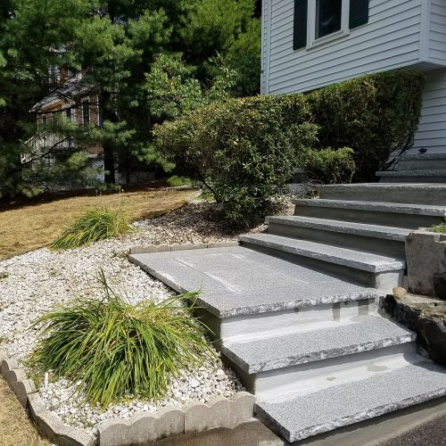 Stone steps leading to a house with a well-maintained lawn, creating an inviting entrance.